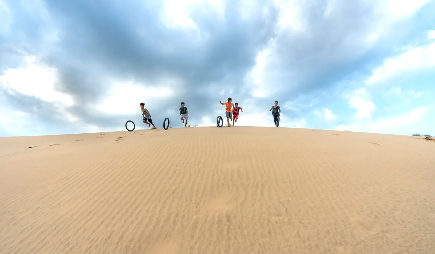 Children playing and running down sand dunes during a desert excursion