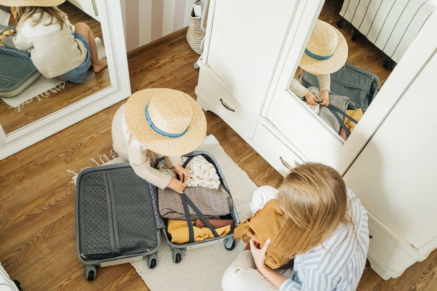 A parent helping a child pack a suitcase in preparation for a family desert trip