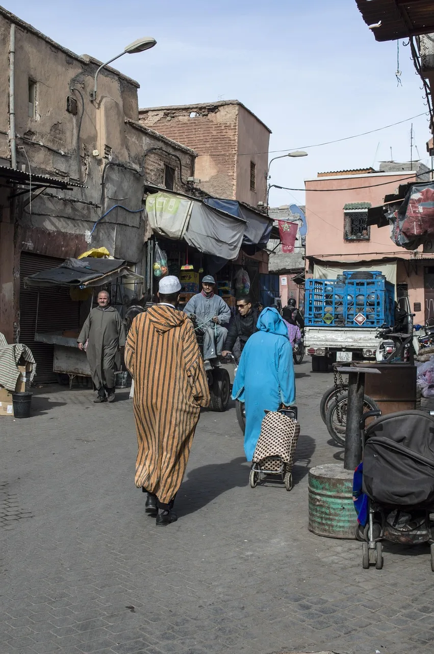 A busy Moroccan medina street market with vendors and shoppers.